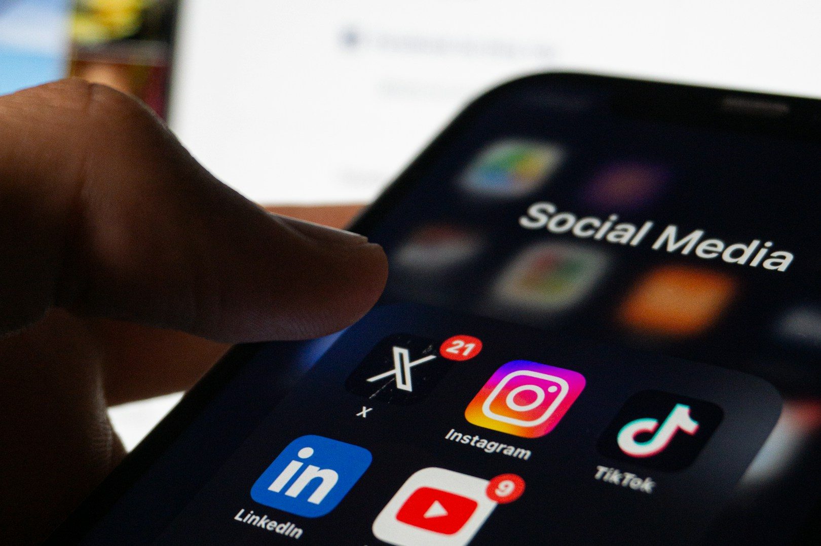 Eine Hand tippt auf sozialen Medien-Icons auf einem Smartphone-Bildschirm.