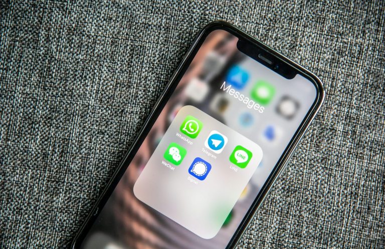 Smartphone mit App-Ordner, enthält Symbole von WhatsApp, Signal und Telegram.