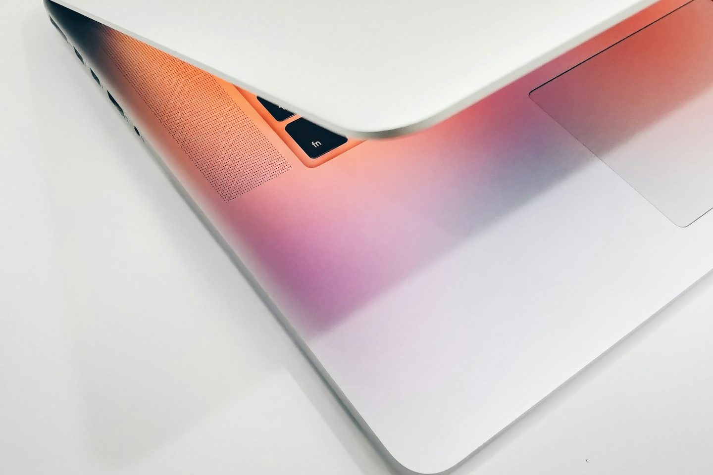 Ein geöffneter Laptop mit einem Farbverlauf von Rosa zu Weiß.